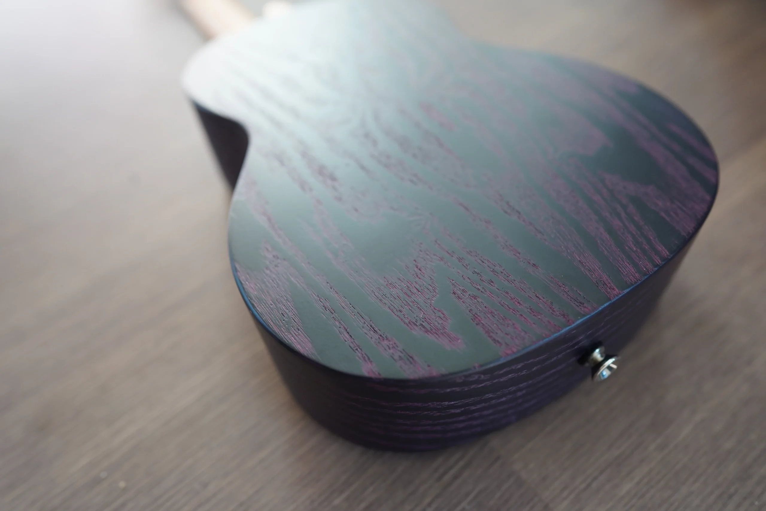 Angled close-up of the Flight DUC 400 Ash Purple ukulele back displaying the textured purple ash wood grain.