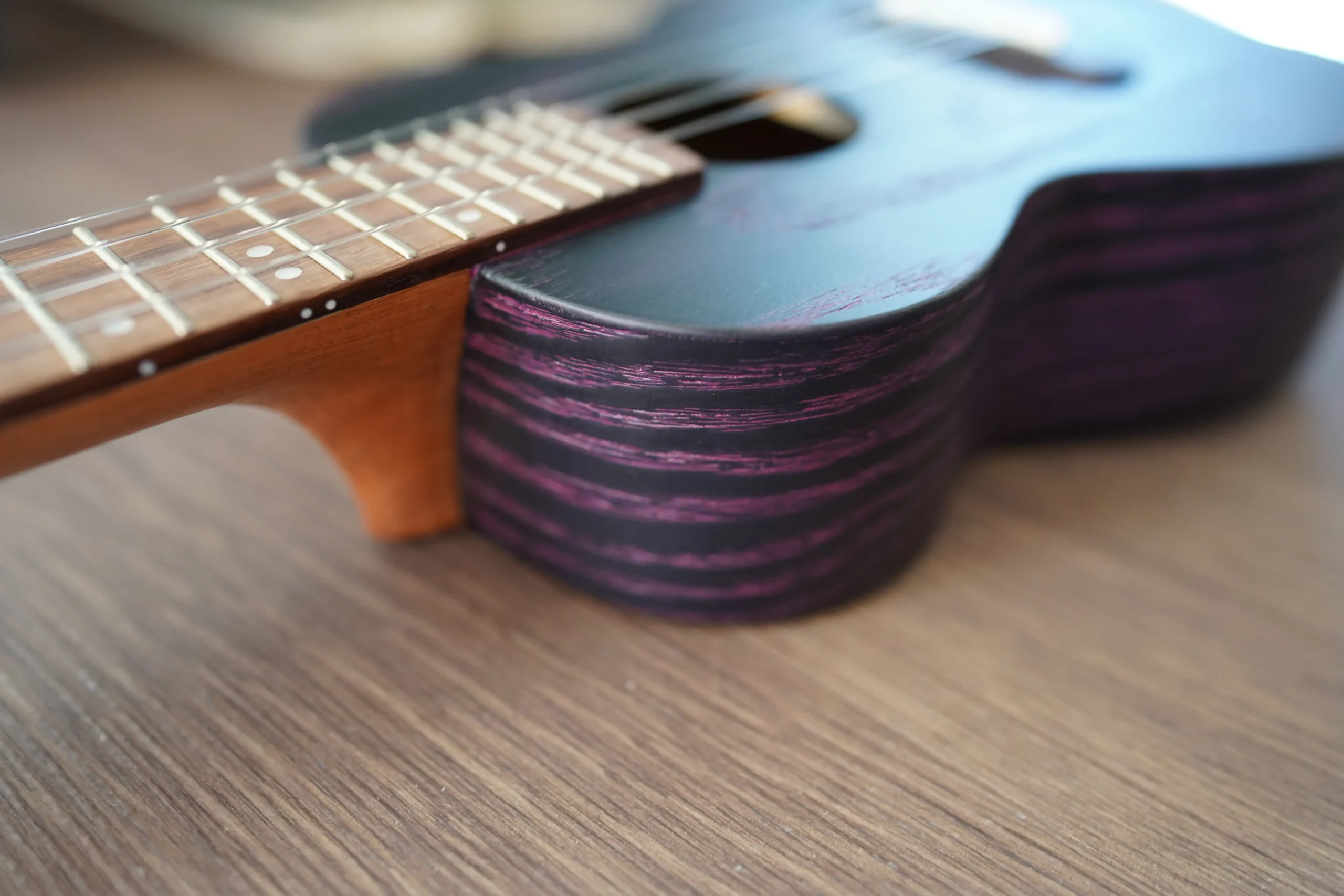 Side profile of the Flight DUC 400 Ash Purple ukulele showing the body depth, purple ash grain, and neck joint.