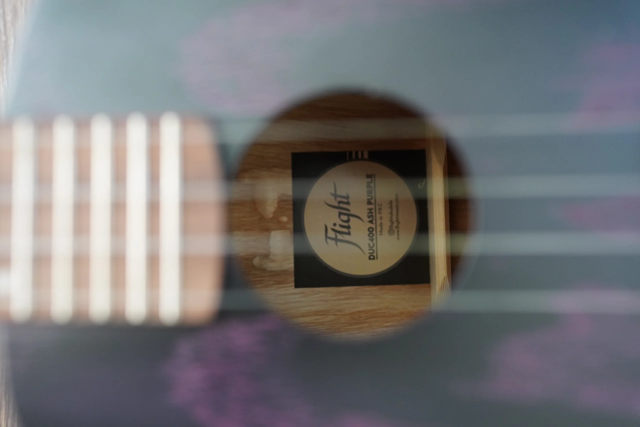 Close-up of the Flight DUC 400 Ash Purple ukulele soundhole showing the Flight logo and interior label.