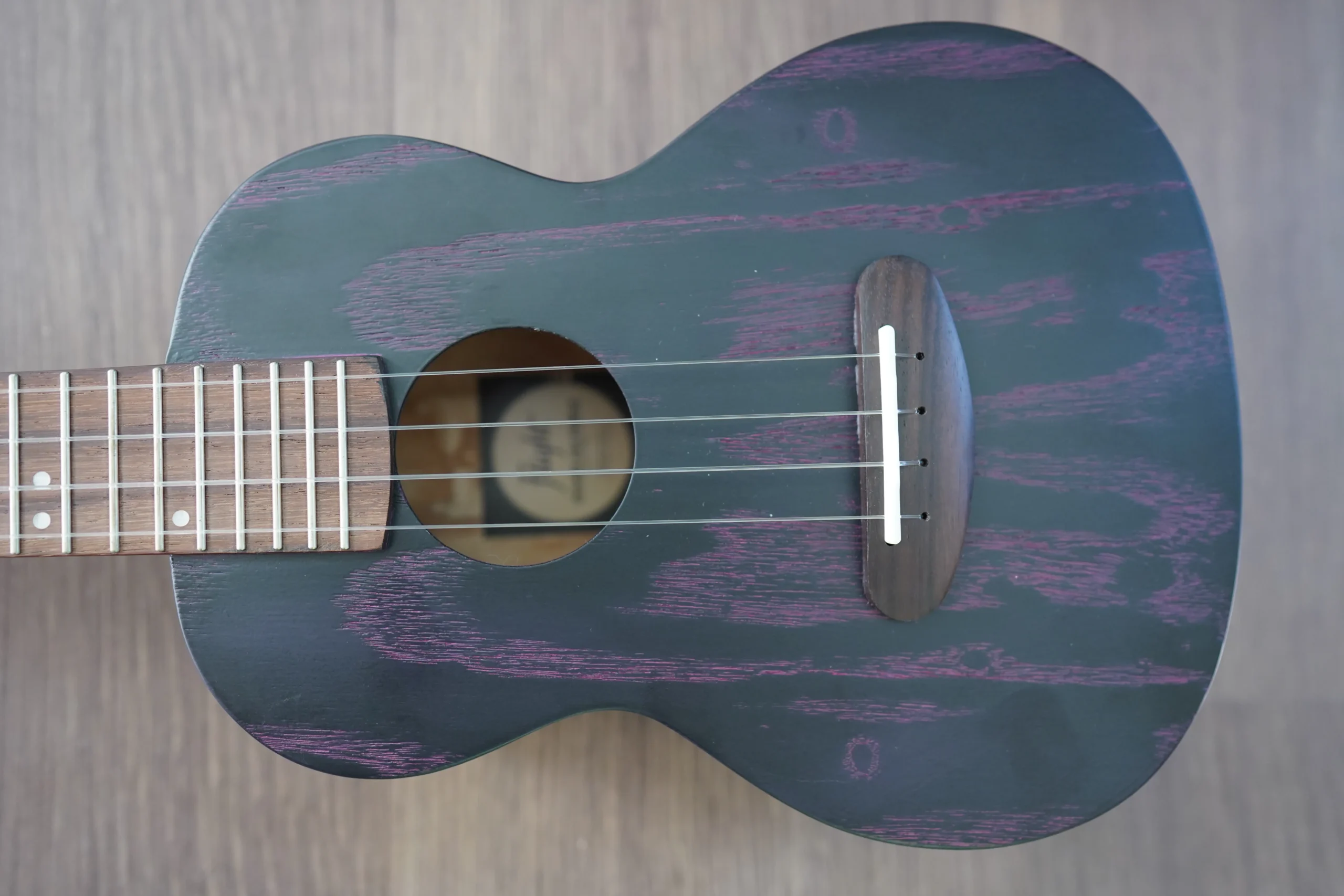 Top view of the Flight DUC 400 Ash Purple concert ukulele showcasing the ash wood grain, bridge, and soundhole.